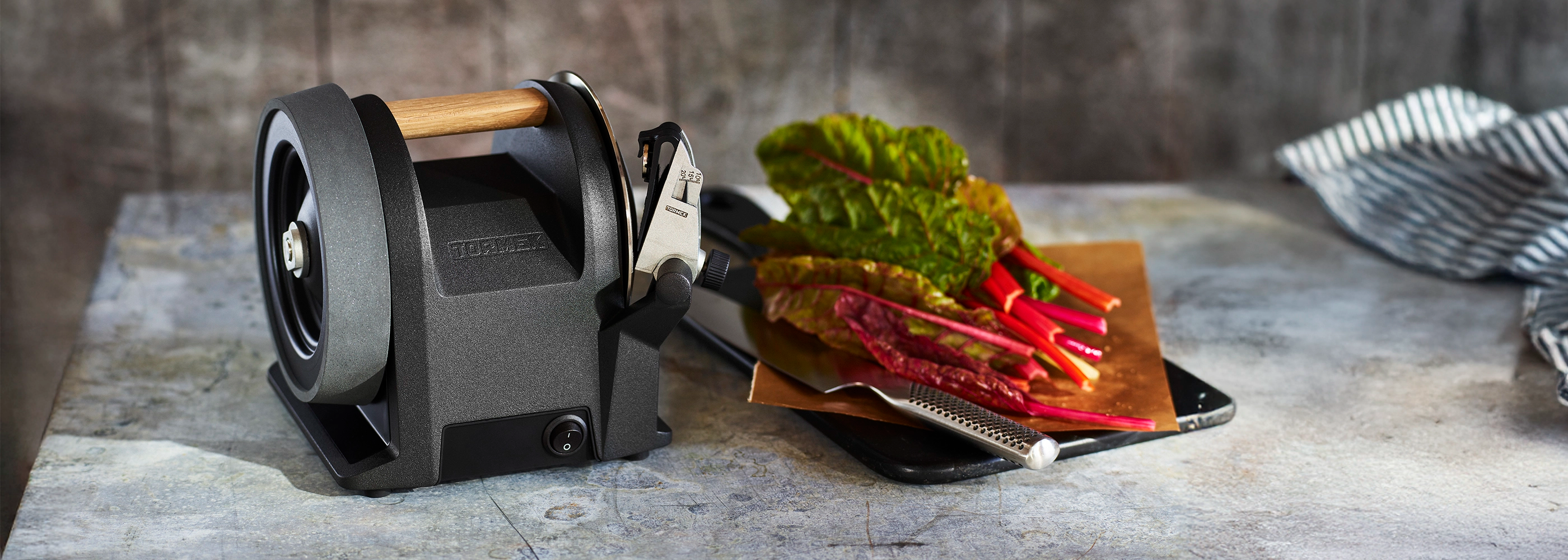 Tormek T-1 Kitchen Knife Sharpener on a kitchen counter next to a chopping board filled with swiss chard