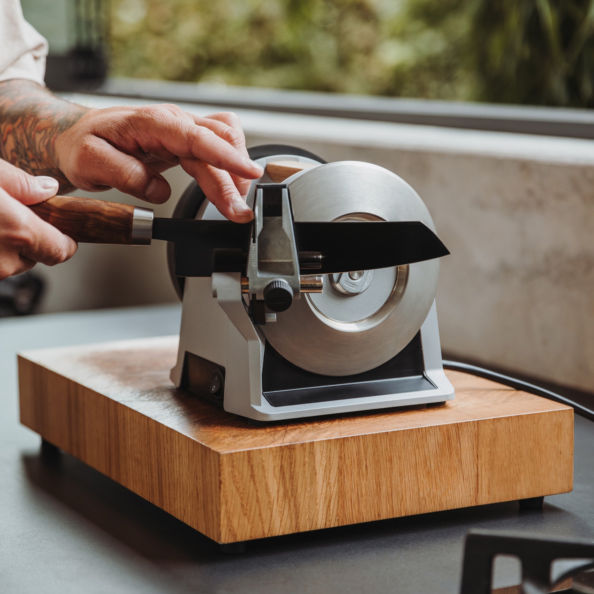 A person sharpening a knife on the Tormek T-1 Zinc Gray